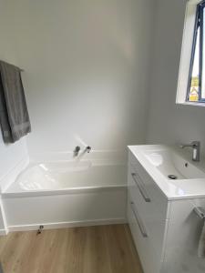 a white bathroom with a tub and a sink at Mangōnui Harbour Haven in Mangonui