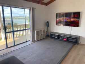 a living room with a flat screen tv and a large window at Mangōnui Harbour Haven in Mangonui