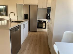 a kitchen with white cabinets and stainless steel appliances at Mangōnui Harbour Haven in Mangonui +2 photos