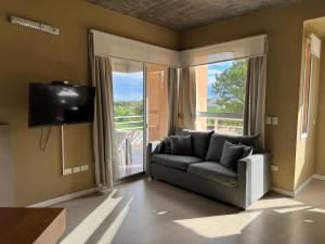 a living room with a couch and a sliding glass door at Lomas del Real Apart in Colonia del Sacramento