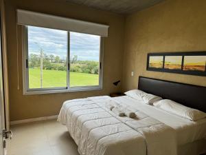 a bedroom with a large bed with a large window at Lomas del Real Apart in Colonia del Sacramento +81 photos