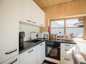 a kitchen with white cabinets and a black counter top at Modern chalet with sauna, Dein Bichlbach in Bichlbach +16 photos