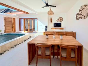 a dining room with a table and a swimming pool at Yamore Villa in Gili Islands