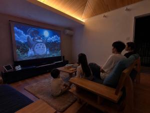 a group of people sitting in a living room watching tv at Smile House Akiya in Hayama