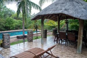 a patio with a large umbrella and chairs next to a pool at Tamboti House in Malelane