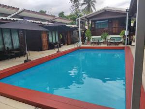 a large blue swimming pool in front of a house at Chuchaiburi Sri Amphawa in Amphawa