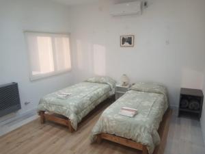 a bedroom with two beds and a window and a tv at El mejor descanso lll in Plottier