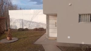 a white building with a door in a yard at El mejor descanso lll in Plottier