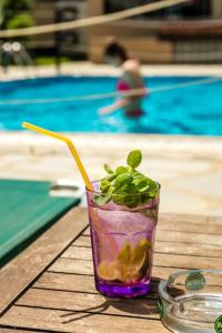 a drink sitting on a table next to a swimming pool at Green Sea Apartments in Skala Potamias