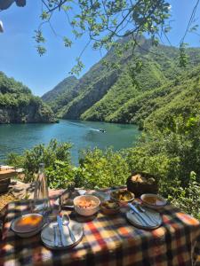 a picnic table with food and a view of a river at Norral shelter 1 in Kajvall