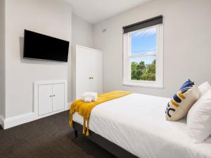 a white bedroom with a bed and a window at Heritage-Style Boutique Hotel, Port Melbourne in Melbourne