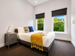 a white bedroom with a bed and two windows at Heritage-Style Boutique Hotel, Port Melbourne in Melbourne