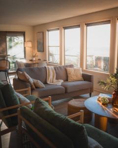 a living room with a couch and tables and windows at Private Blufftop Oceanview Hot Tub Fire Pit in Port Angeles