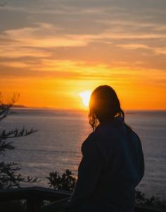 a woman looking out at the sunset on the ocean at Private Blufftop Oceanview Hot Tub Fire Pit in Port Angeles +67 photos