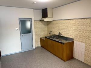 an empty kitchen with a sink and a door at PREGOROOM in Osaka
