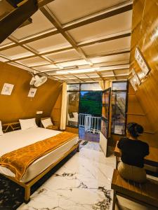 a woman sitting next to a bed in a room at Vagamon leafmist frame cabin in Vagamon