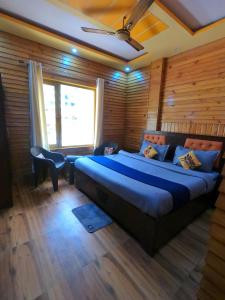 a bedroom with a large bed in a room with wooden walls at Bagwan Kainchi Stay in Bhowāli