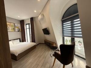 a bedroom with a bed and a chair and a window at VIN HOTEL in Vĩnh Long