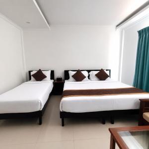 two beds in a room with two windows at HOTEL SQUARE INN Cosmopolitan in Bangalore