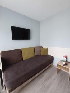 a couch in a living room with a tv on a wall at Santa Maria in Kołobrzeg +15 photos