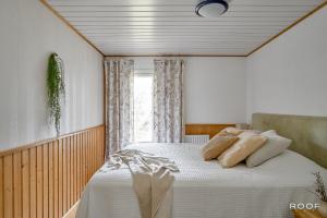 a bedroom with a bed with white sheets and a window at Villa Repovesi in Hillosensalmi