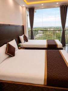 two beds in a room with a large window at HOTEL SAMAY Rajgir in Rājgīr