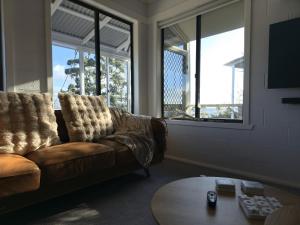a living room with a couch and a table and windows at Tide & Timber - Adventure Bay in Adventure Bay