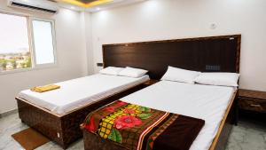 a bedroom with two beds and a window at HOTEL SAMAY Rajgir in Rājgīr