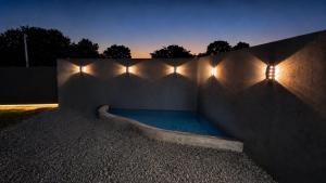 a swimming pool with lights on a wall at night at Chalé Queen in Brasília