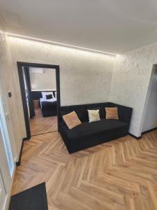 a living room with a black couch and a mirror at Prime Luxury Apartman in Mátészalka