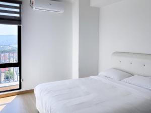 a white bedroom with a white bed and a window at Atlas Serviced Suites in Butterworth