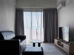 a living room with a couch and a television at Atlas Serviced Suites in Butterworth