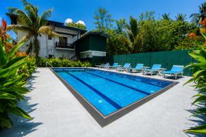 a swimming pool with chairs and a house at Lion See Hotel - Sigiriya in Sigiriya