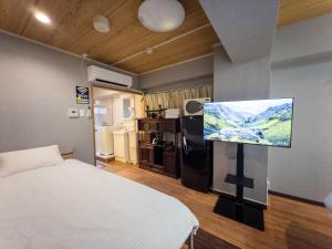 a bedroom with a bed and a flat screen tv at KANDA HOUSE!! Shin-Okubo Walkable Modern Stay with Shinjuku Access in Tokyo