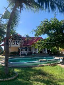 a swimming pool in front of a house with a palm tree at Dumaguete Dive Center in Mojon