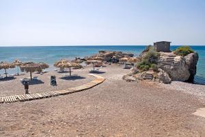 a beach with umbrellas and chairs and the ocean at Corafili Holiday Suites in Kiotari