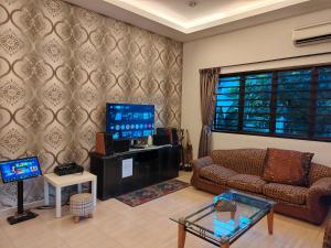 a living room with a couch and a tv at MELAKA BEACH VILLA ( A TYPE ) in Kelebang Besar