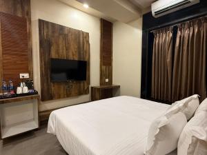 a bedroom with a bed and a flat screen tv at Hotel Ashoka Inn in Wardha