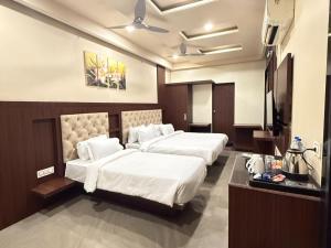 a hotel room with two beds and a television at Hotel Ashoka Inn in Wardha