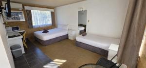 a small room with two beds and a desk at Hamilton Hume Motor Inn in Yass