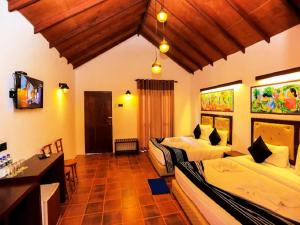 a bedroom with two beds and a desk and a television at Four Points Resort - Anuradhapura in Anuradhapura