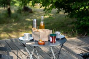 a table with a bottle of beer and a basket of bread at Roulotte de Combeplane in Carnac-Rouffiac