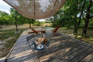 a wooden deck with a table and chairs on it at Roulotte de Combeplane in Carnac-Rouffiac