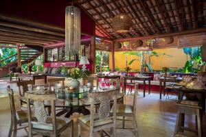 a restaurant with tables and chairs in a room at Pousada Hibisco in Trancoso