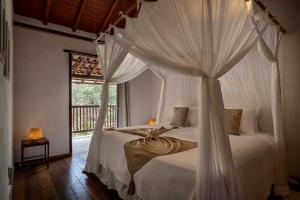 a bedroom with a canopy bed with a window at Pousada Hibisco in Trancoso +98 photos