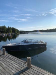 a boat sitting on the water next to a dock at Spectacular lake plot, Stockholm archipelago in Dalarö
