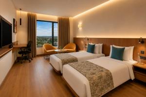 a hotel room with two beds and a television at The Fern Residency, Jamnagar, Series by Marriott in Jamnagar
