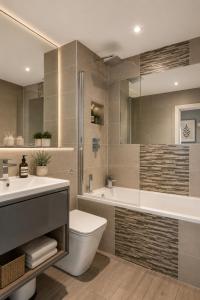 a bathroom with a tub and a toilet and a sink at Airhost's Brighton's Best Green Diamond Escape with Sea Views in Brighton & Hove +134 photos