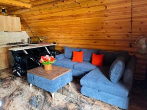 a living room with a blue couch and a table at Eco cottage in Borjomi with pool 2 in Sadgeri