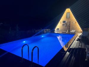 a swimming pool at night with a house at Eco cottage in Borjomi with pool 2 in Sadgeri